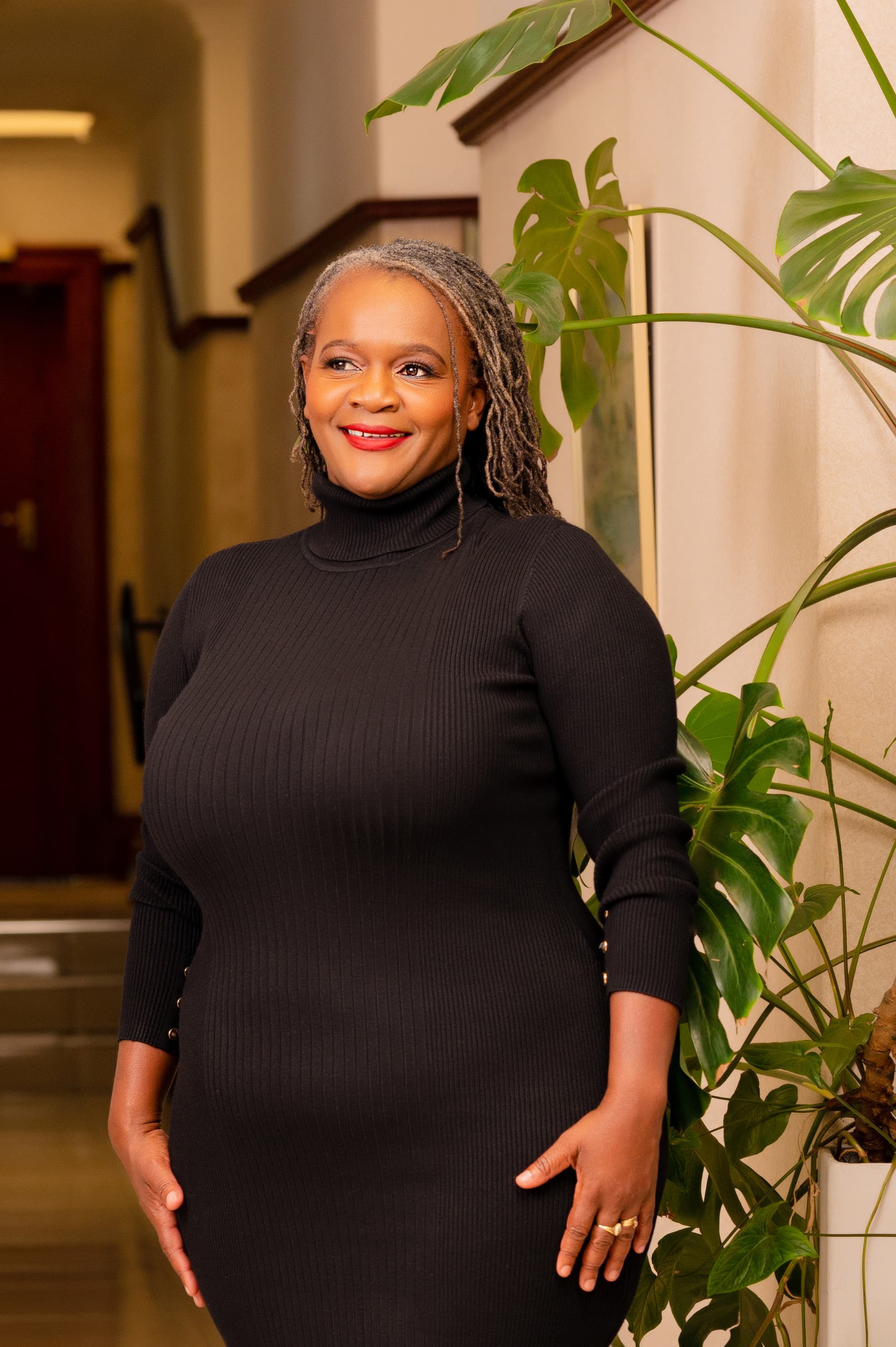 Clara Mlambo standing in an office corridor portrait.